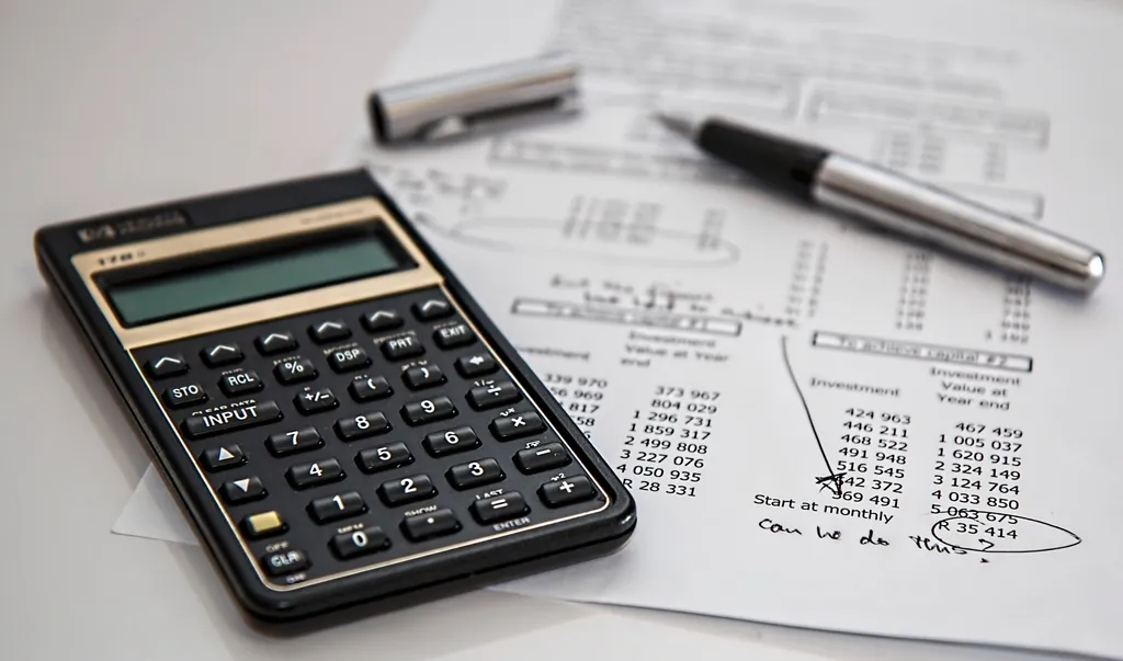 Calculator and pen resting on a printed statement of figures