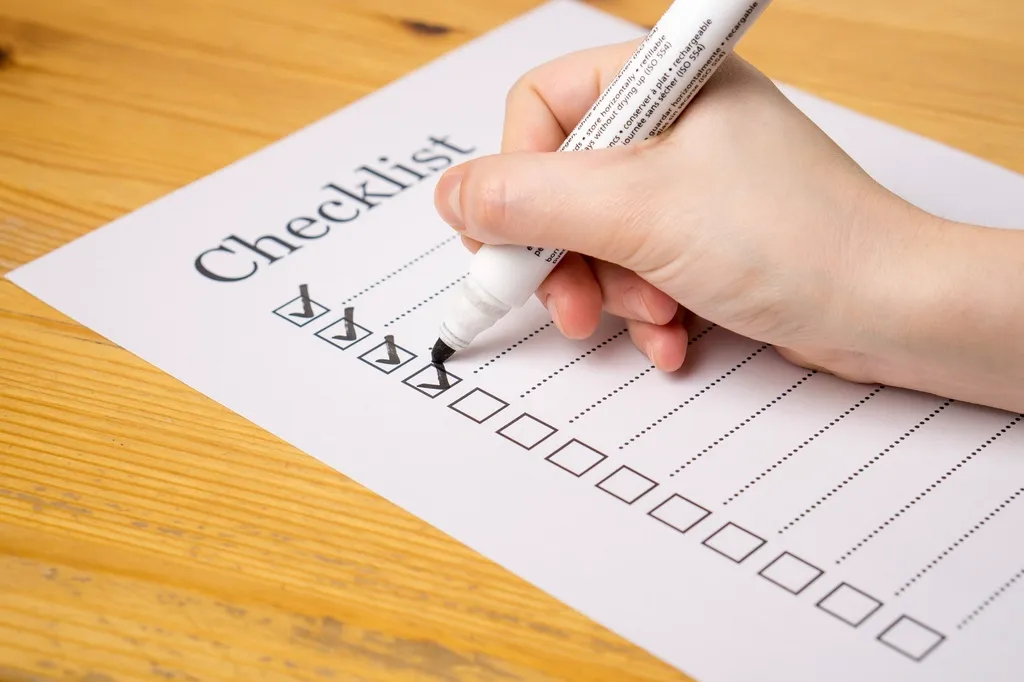 Hand ticking boxes on a paper checklist