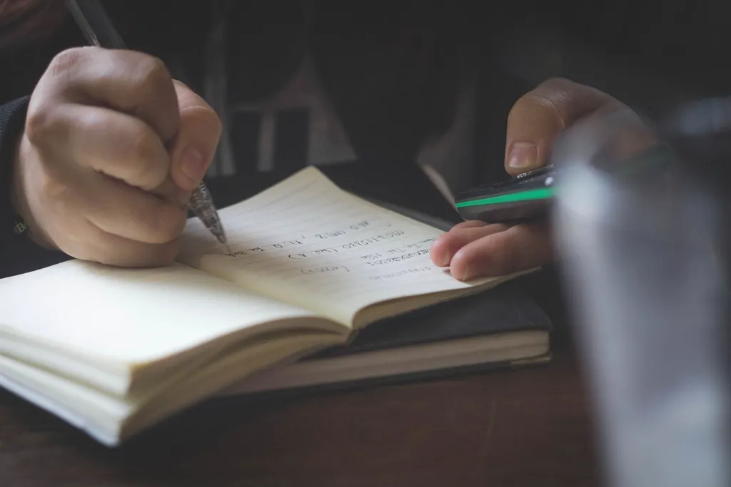 Mains écrivant au stylo dans un carnet ouvert
