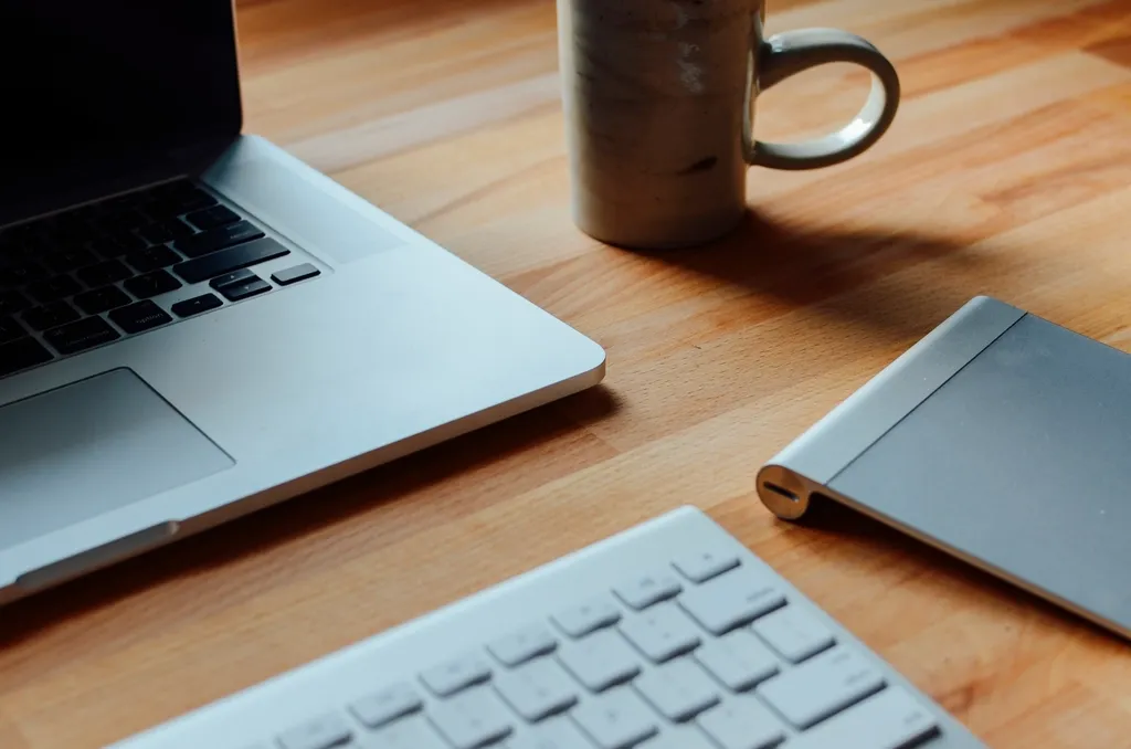 Ordinateur portable, clavier, pavé tactile et tasse sur un bureau en bois