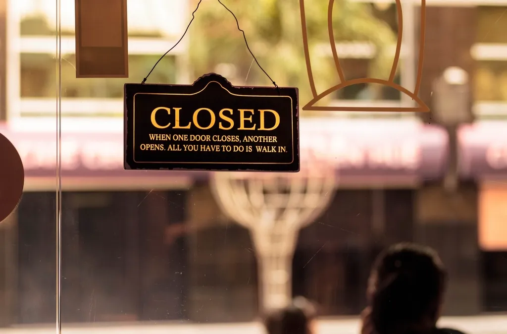 Golden "Closed" sign hanging in a shop window