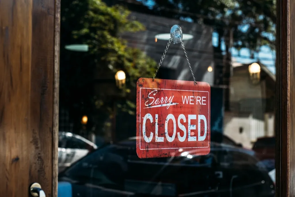 Panneau rouge « Sorry we're closed » suspendu derrière une vitrine