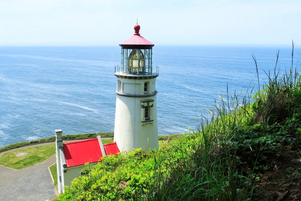 Phare blanc à toit rouge sur une falaise verdoyante face à la mer