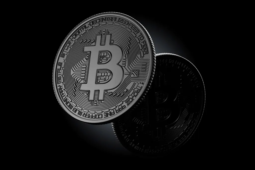 Pièce argentée frappée du symbole bitcoin sur fond noir