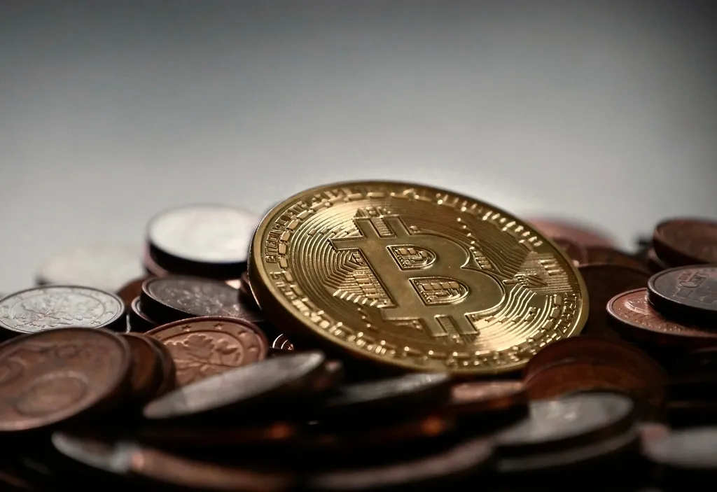 Pièce dorée frappée du symbole bitcoin posée sur un tas de pièces
