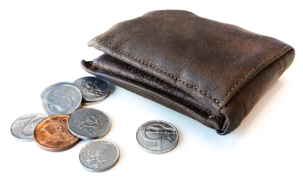Portefeuille en cuir usé d'où sortent des pièces de monnaie