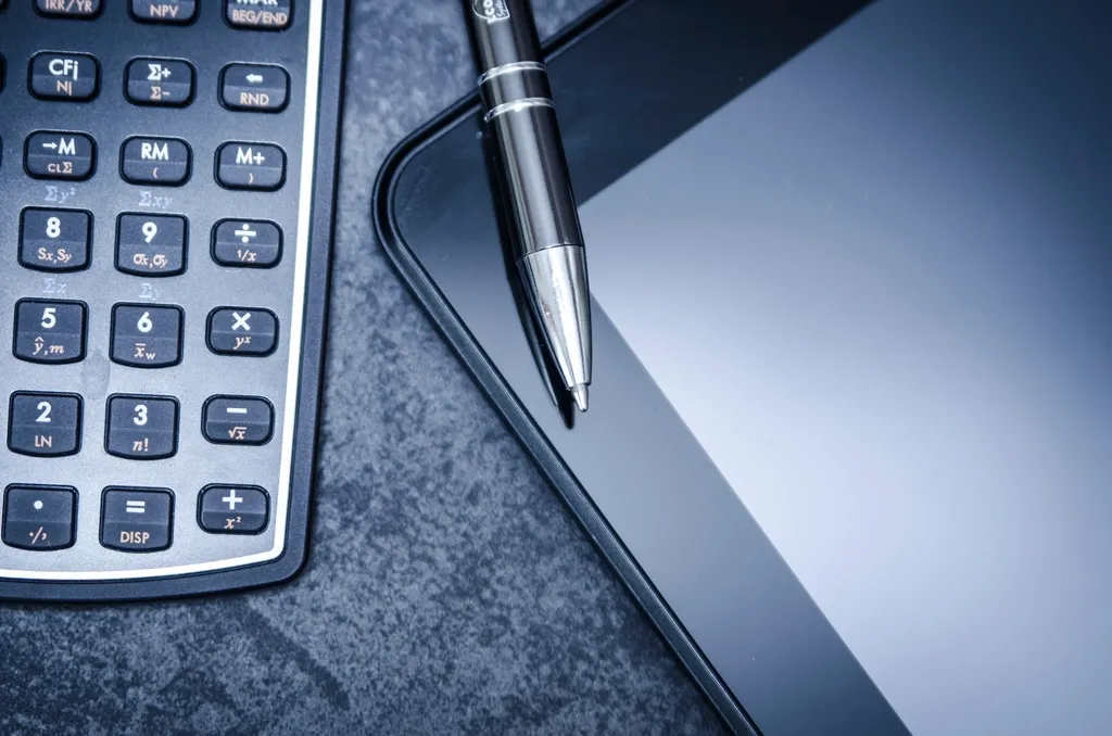A calculator and pen resting on a tablet