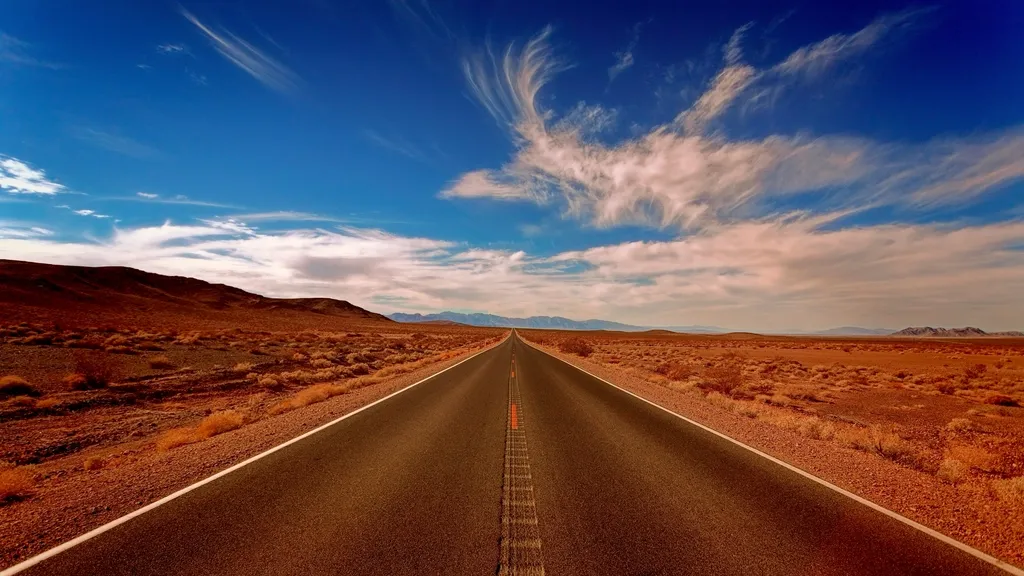 Straight road crossing a desert under a blue sky