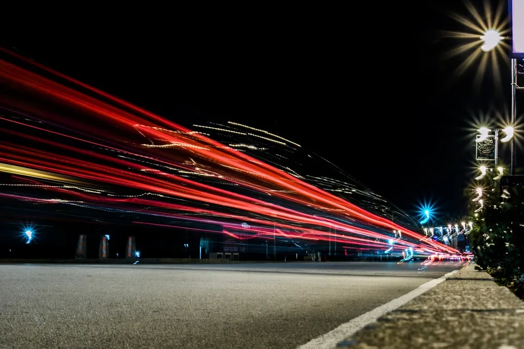 Traînées lumineuses rouges de voitures sur une route la nuit