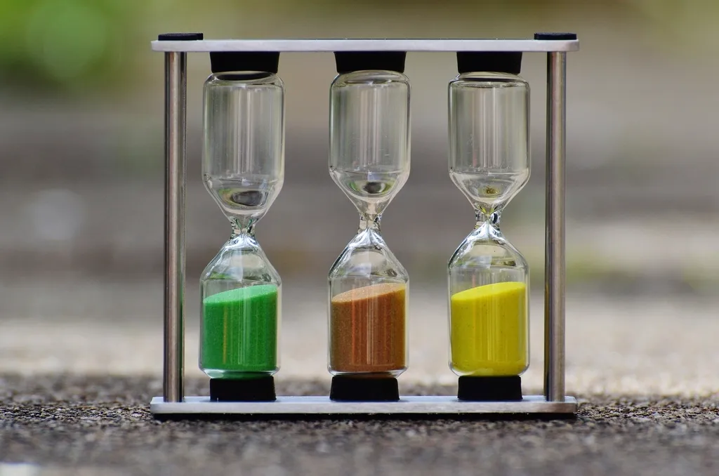 Three hourglasses in a metal frame on a light background
